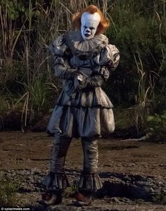 a creepy clown is standing in the dirt