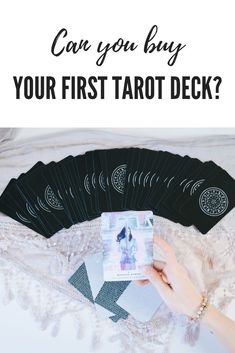 a person holding up some cards with the text can you buy your first tarot deck?