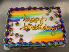 a birthday cake with rainbow frosting and the words happy birthday written in large letters