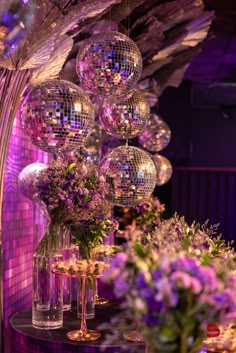 disco balls hanging from the ceiling and vases filled with flowers on top of a table