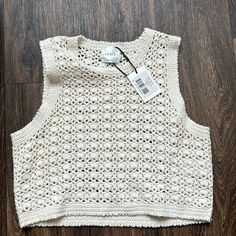 a white knitted tank top on a wooden floor with a tag attached to it