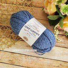 a blue ball of yarn sitting on top of a wooden table next to flowers and a vase