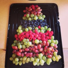 grapes and raspberries arranged in the shape of a christmas tree on a tray