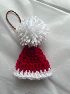 a red and white crocheted christmas ornament with a candy cane sticking out of it