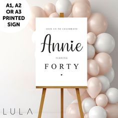 an easel with balloons and a sign that says annie turning forty