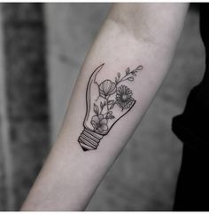 a black and white photo of a light bulb with flowers on it's arm