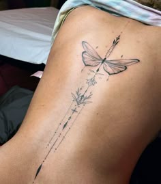 a woman's back with a dragonfly tattoo on her lower back and side