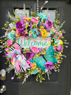 a welcome sign is hanging on the front door with colorful flowers and ribbons around it