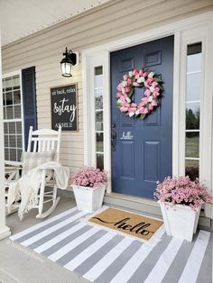 a blue front door with a pink wreath and welcome mat on the porch next to it