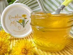 a jar filled with honey sitting on top of a table next to some yellow flowers