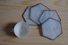 three glass plates sitting on top of a wooden table next to a cup and saucer