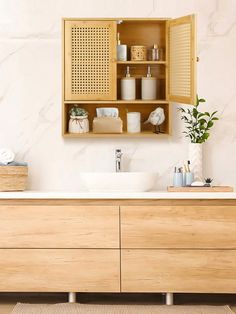 a bathroom with a sink and wooden cabinet above it's counter top, next to a towel dispenser on the wall