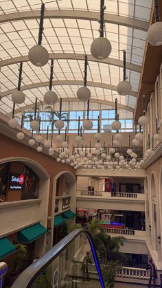 the inside of a shopping mall with lights hanging from the ceiling