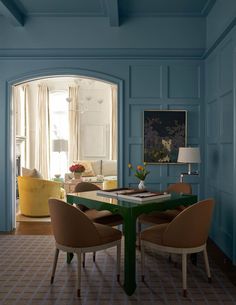 a living room with blue walls and chairs around a green table in front of an open doorway