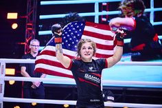 a woman is holding an american flag in her hands while standing next to a boxing ring