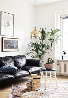 a black leather couch sitting in a living room next to a table and potted plant