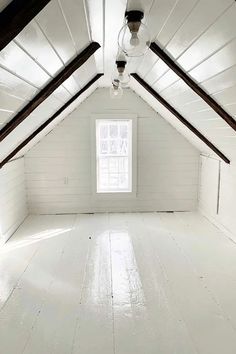 an empty attic with white walls and wood beams on the ceiling is seen in this image