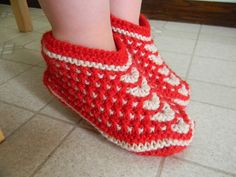 a close up of a child's feet wearing crocheted shoes on the floor