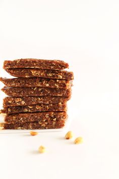 a stack of granola bars sitting on top of a white plate next to nuts