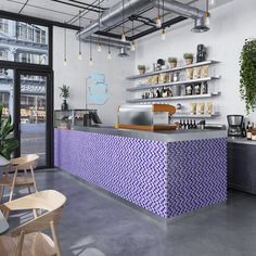 the interior of a coffee shop with purple tiles on the counter and shelves above it