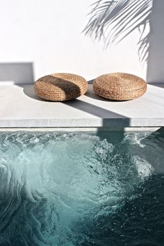 two wicker cushions sit on the edge of a swimming pool