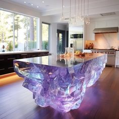 a large kitchen with an island made out of glass blocks and lights hanging from the ceiling