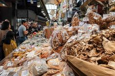 many people are shopping at the market with bags full of food in front of them