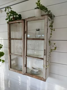 an old window is filled with wine glasses and greenery on the outside of it