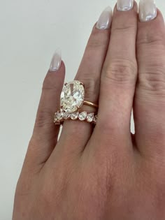 a woman's hand holding an engagement ring with two diamonds on top of it