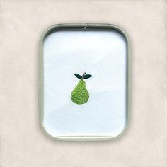 an embroidered pear on a white background in a square frame with a green leaf sticking out of it