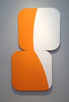 two orange and white coasters sitting on top of each other in front of a gray wall