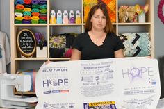 a woman holding up a large sign in front of some crafting supplies on shelves