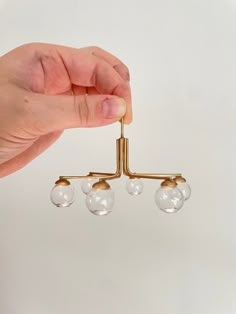 a hand holding a brass chandelier with five glass balls