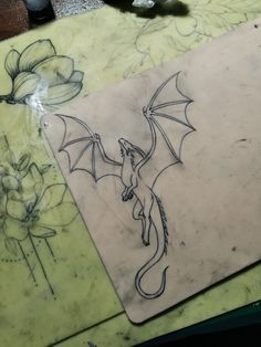 a drawing of a dragon on a piece of paper next to some pens and scissors