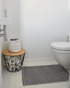 a white toilet sitting next to a black and white rug