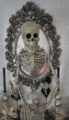 a mirror with a skeleton in it and candles on the table next to it,