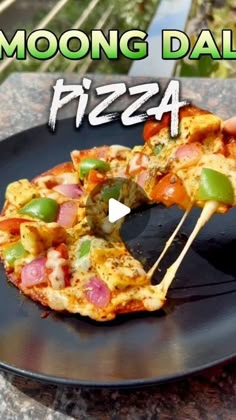 a black plate topped with a pizza covered in toppings