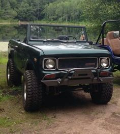 a green truck parked on top of a dirt road