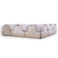 an upholstered couch with multiple pillows on the back and sides, in light grey fabric