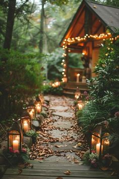 candles are lit on the path leading to a small cabin in the woods with trees and foliage