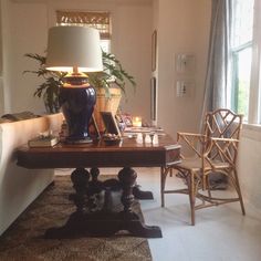 a living room filled with furniture and a lamp on top of a wooden table in front of a window