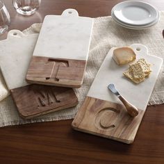 three wooden cutting boards sitting on top of a table next to wine glasses and plates