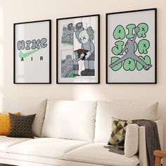 three framed pictures hang on the wall above a white couch in front of a window