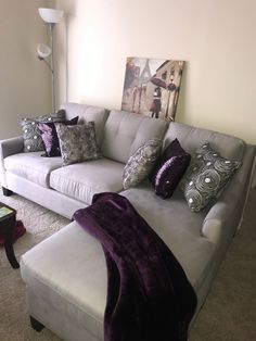 a white couch with purple and silver pillows