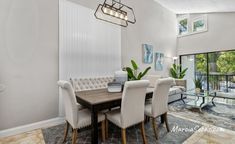 a dining room table with white chairs next to a glass door