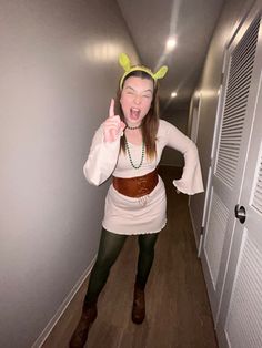 a woman in a costume is making the peace sign with her hands while walking down a hallway