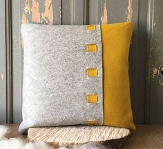 a gray and yellow pillow sitting on top of a wooden table