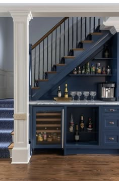 an open bar with wine glasses and bottles on it in front of the stair case