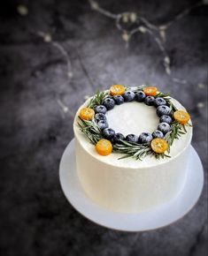 a white cake topped with blueberries and oranges