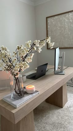 there is a vase with flowers and candles on the table in front of a laptop